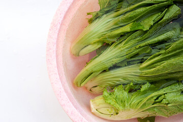 Mustard Green soaked in a pink bowl of water. Wash vegetables