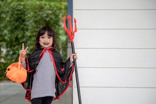 Asian Child Girl In Demon Costume Holding Black And Red Trident, Happy Halloween Concept