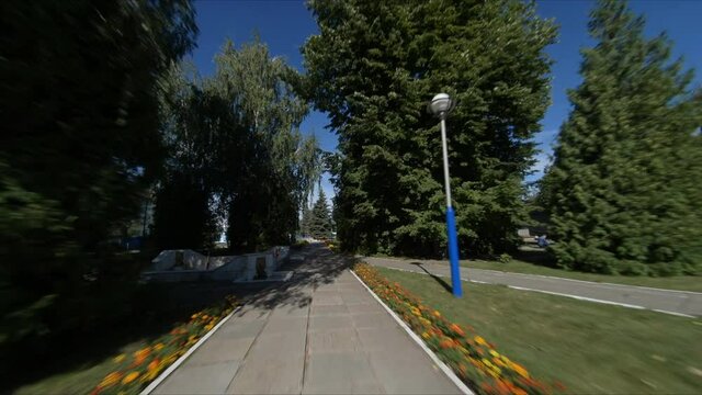 Motion along empty park road with air pipelines about territory of industrial complex with lawns and flowers aerial first point view