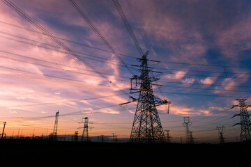 A silhouette of an electric tower against a beautiful sunset background