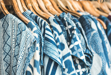 Selective focus tie dye shirts in blue white clothing hanging on rack.