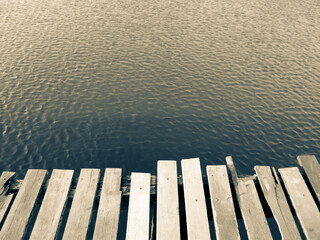 Mole (pier) on the lake. Wooden bridge in forest in spring time with blue lake. Lake for fishing with pier. Dark and Foggy lake nature beautiful background