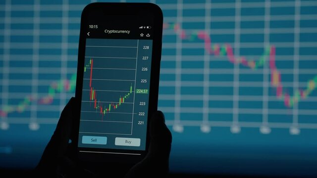 a professional broker looks at a detailed chart of cryptocurrency price changes on the screen of a mobile phone against the background of other charts of the stock exchange - Powered by Adobe