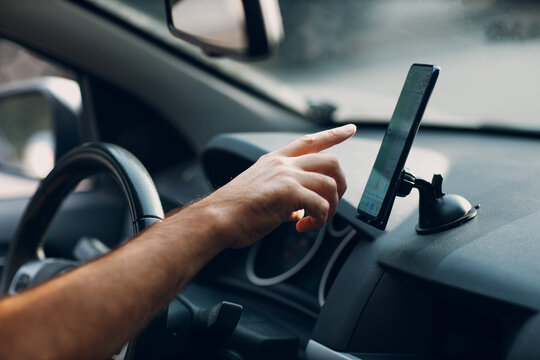 Navigator in car vehicle transportation commuter. Driver man pointing hand finger mobile phone navigator app while driving car.