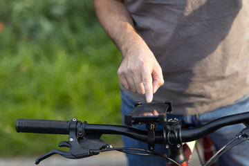 Man planning route using GPS navigation application in mobile phone on his bicycle bike