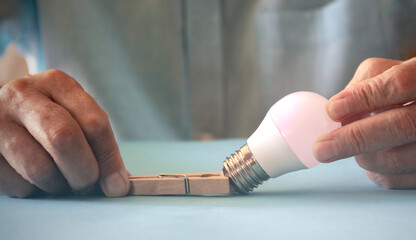 Light bulb caught with clothespins. Energy saving concept. Copy space. Selective focus.