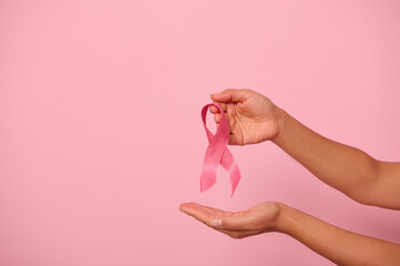 Woman hands holding a pink ribbon, symbol of World Breast Cancer awareness Day, in 1 st October. Woman's health and medical concept, October Pink day, World Cancer Day, national Cancer Survivor Day.