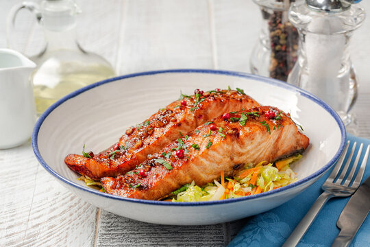 Honey garlic glazed salmon with vegetables in a white plate, white table. Healthy food concept.