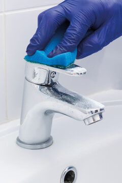 an employee of a cleaning company is cleaning and washing the faucet and sink, close-up