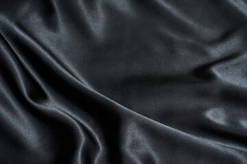 Black wavy silk background. Satin fabric texture. Dark elegant rich backdrop. Delicate design. Shine decoration christmas material. Tender art drape. Beautiful romantic textile