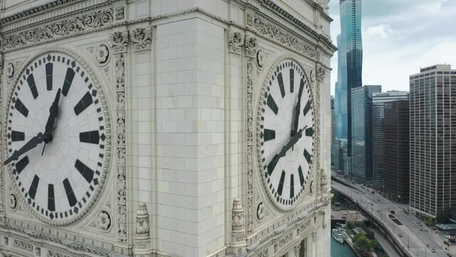 Aerial close up of the white marble city tower with huge clock. Scenic city clock with Chicago downtown on motion background on cloudy summer day. Cinematic Chicago river walk 4K footage.