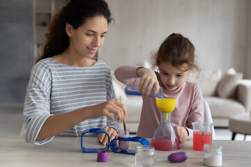 Happy caring young hispanic mother making chemical experiments or tests with smart cute kid daughter, improving knowledge, enjoying studying together in playful manner, homeschooling education concept