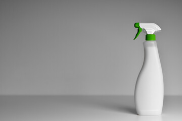 White spray plastic bottle of cleaner antiseptic on a grey background with a green cap. Space for...