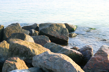 Fototapeta na wymiar Large stones close-up in sea water in summer on beach against background of sea