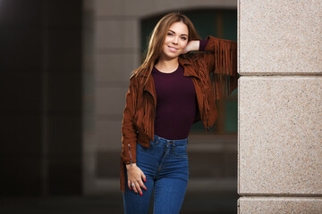 Young fashion woman in leather fringe suede jacket and dark blue jeans - Powered by Adobe