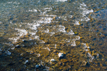 Crystal clear water over creek bed and colourful pebbles.