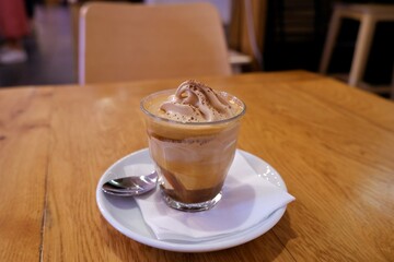 Eis cream coffee in glass pot on a white plate on a brown table with brown chairs