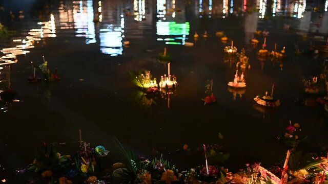 Paper lotus flower with candle floating on a river at night in Loy krathong festival, traditional Siamese new year festival celebrated in Thailand.