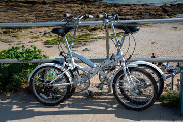 Fototapeta na wymiar Cornwall, England, UK. 2021. Two folding cycles locked to railings at a seaside resort for safety.