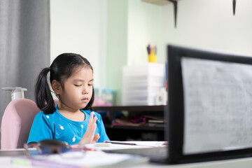 Asian child student or kid girl count numbers by finger hand to maths learning and study online or learn from home on computer notebook or video call on laptop to mathematics class by back to school