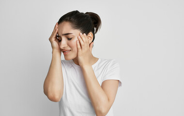 brunette in a white t-shirt holding her head migraine stress depression