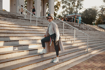 stylish fashionable woman walking in street in elegant style coat