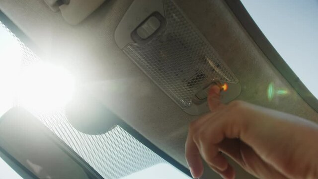 Person presses the button to close the sunroof in the car, close up.