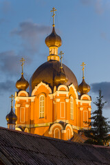 Fototapeta na wymiar Illuminated top of the old Church of the Exaltation of the Cross in August twilight. Tikhvin Assumption Monastery of the Theotokos. Leningrad region, Russia