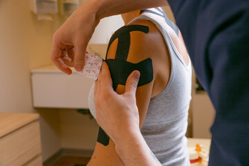 Doctor osteopath masseur treating a girl with taping, manual therapy