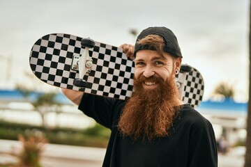 Young irish skater man smiling happy holding skate at the city. © Krakenimages.com