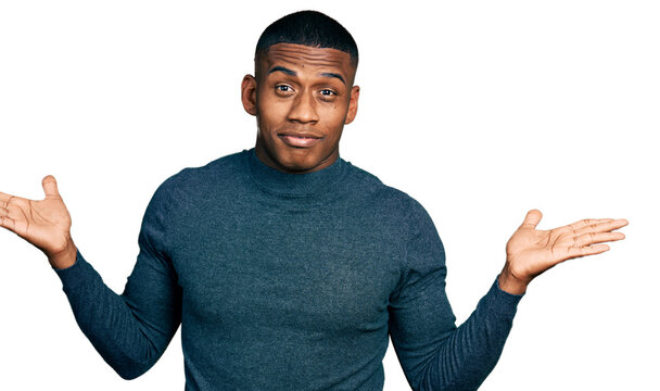 Young black man wearing casual sweater clueless and confused with open arms, no idea and doubtful face.
