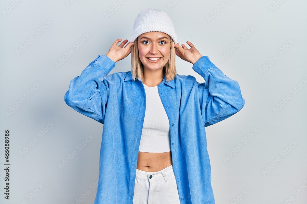 Sticker beautiful blonde woman wearing wool hat smiling pulling ears with fingers, funny gesture. audition p