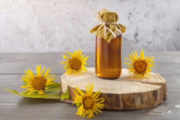 a bottle of homemade tincture of elecampane and flowers on a wooden background