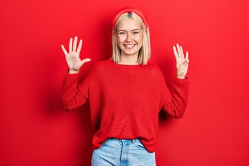 Beautiful blonde woman wearing casual red sweater showing and pointing up with fingers number nine...