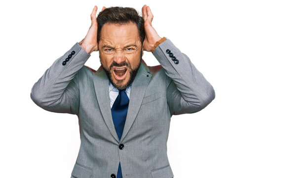 Middle age man wearing business clothes crazy and scared with hands on head, afraid and surprised of shock with open mouth