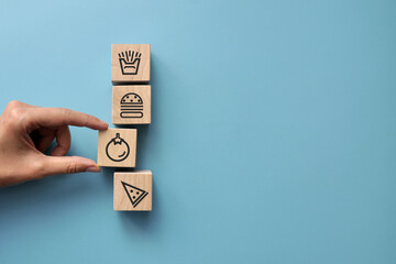 Wooden cubes with drawings of harmful and healthy food. Choosing vegetables among fast food