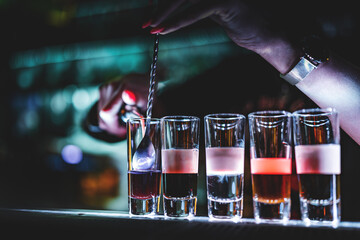 bartender hand making collection of colorful shots. Set of cocktails at the bar counter