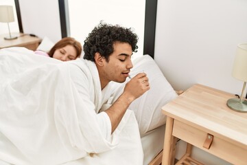 Obraz premium Young couple slepping on the bed at bedroom. Man drinking glass of water.