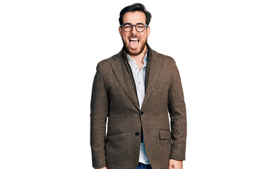 Young hispanic man wearing business jacket and glasses sticking tongue out happy with funny expression. emotion concept.