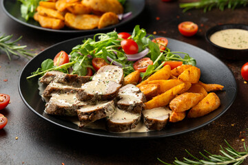 Roast Pork Tenderloin in mustard gravy with vegetables and potato wedges