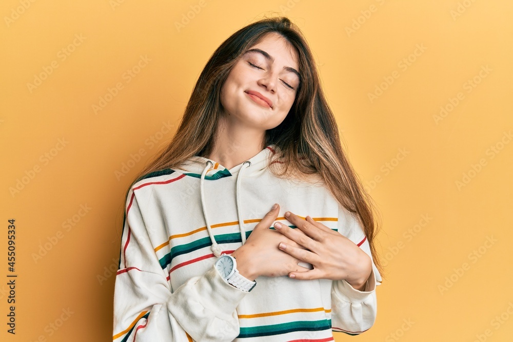 Poster Young caucasian woman wearing casual clothes smiling with hands on chest with closed eyes and grateful gesture on face. health concept.