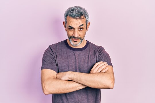 Handsome middle age man with grey hair wearing casual t shirt skeptic and nervous, disapproving expression on face with crossed arms. negative person.