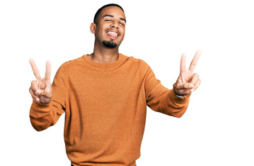 Young african american man wearing casual clothes smiling with tongue out showing fingers of both hands doing victory sign. number two.
