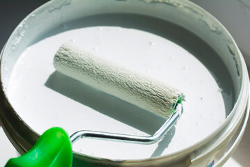 Foam roller and white paint bucket for painting. Minimal construction concept. Defocused blurred...
