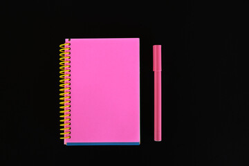 Pink notebook and pen on black background