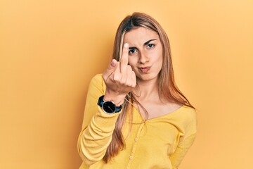 Beautiful hispanic woman wearing casual yellow sweater showing middle finger, impolite and rude...