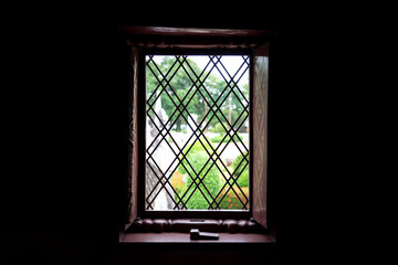 Fototapeta premium Square window frame with metal line fence - looking though outside, selective focus on the fence. Photo contain high contrast ratio due to sun light and shadow.