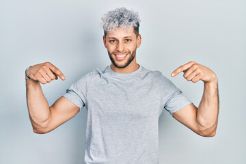 Young hispanic man with modern dyed hair wearing casual grey t shirt looking confident with smile...