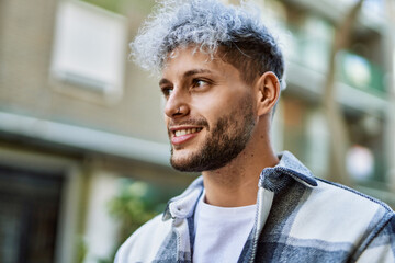 Young hispanic man smiling happy standing at the city.