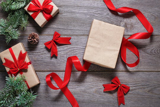 packing christmas gifts on a wooden table, craft paper and red ribbon, free space, new year gifts 2022